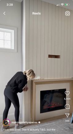 a woman is standing in front of a fireplace