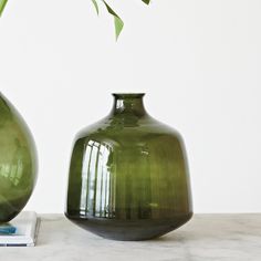 two green vases sitting next to each other on top of a marble countertop