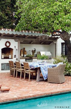 an outdoor dining area next to a pool with chairs and table set up on it