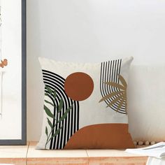 a white pillow sitting on top of a wooden table next to a framed photo and plant