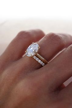 a woman's hand with a diamond ring on top of her finger and an engagement band