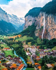 an aerial view of a village in the mountains with a waterfall coming out of it