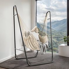 a hammock hanging from a metal frame in front of a window with mountain view