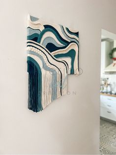 a wall hanging on the side of a white wall with blue and green waves painted on it