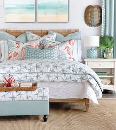 a bedroom with blue and white bedding, two paintings on the wall and a footstool