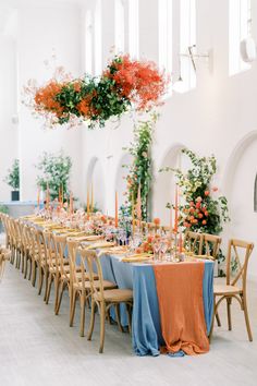 a long table is set with orange and blue linens for an elegant wedding reception