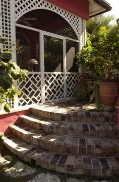 an outdoor area with steps and potted plants on the side of the house that is covered in white trellis