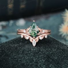 a close up of a ring with a green stone and diamonds on it's side