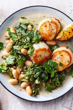 a white plate topped with scallops and greens