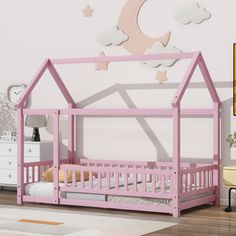 a child's bed with a pink wooden frame and roof shaped like a house