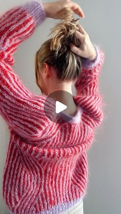 a woman wearing a red and white sweater is holding her hands up to her head