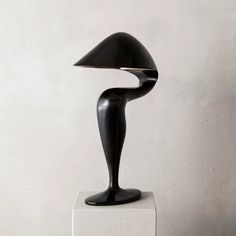 a black sculpture sitting on top of a white block