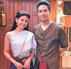 a man and woman standing next to each other in front of a wooden wall with doors