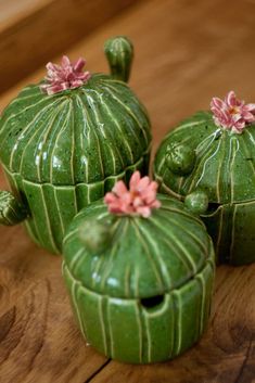 three green ceramic cactus pots sitting on top of a wooden table