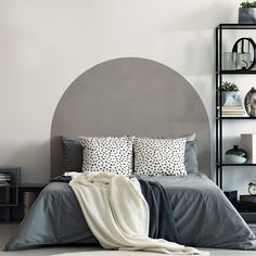 a bed with two pillows on top of it next to a book shelf filled with books