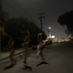 three people are running in the street at night