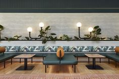 an indoor seating area with plants on the wall and lamps hanging from the ceiling above