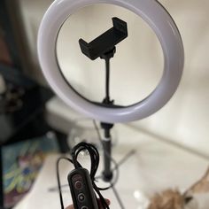 a person holding a remote control in front of a ring light on a table top