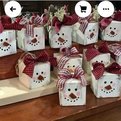 snowman gift boxes with red and white plaid bows on them are sitting on a counter