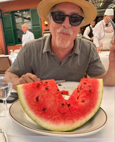 a man sitting at a table with a slice of watermelon in front of him