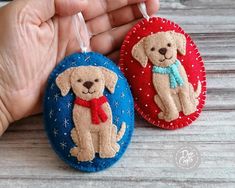 two handmade dog ornaments with red, white and blue designs on them are being held by a person