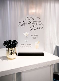 a white table topped with a sign and two glasses