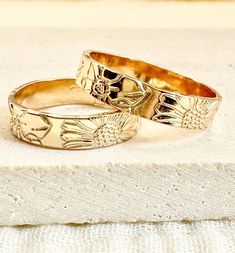 two gold rings sitting on top of a white surface