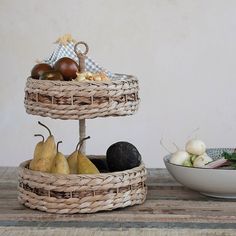 there are two baskets with fruits and vegetables in them on the table next to a bowl