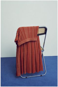 an orange blanket sitting on top of a folding chair