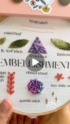 someone is holding up a cross stitch project with different stitches and threads on it