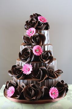 a three tiered chocolate cake with pink flowers on top