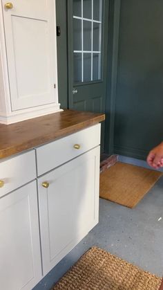 a person standing in front of a kitchen counter next to a brown mat on the floor