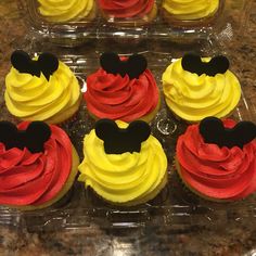 mickey mouse cupcakes with red, yellow and black frosting in plastic cases