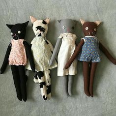 five stuffed animals are lined up in a row on the floor, one is wearing a dress