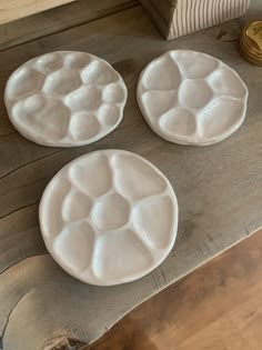 three white plates sitting on top of a wooden table