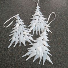 three white plastic christmas trees on a black counter top, one is hanging from a hook