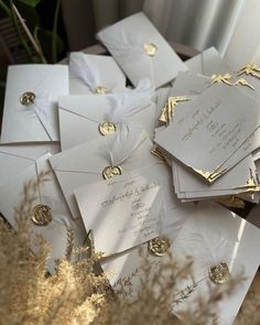 a pile of white and gold wedding cards on top of each other in front of a window