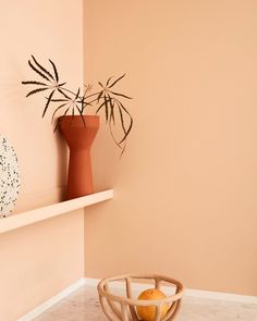 an orange sitting on top of a white shelf next to a vase and fruit bowl