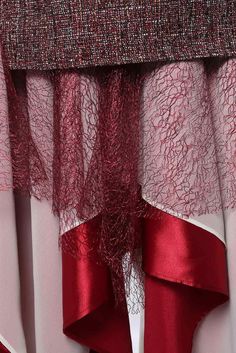 a red and white curtain hanging on the side of a window with sheer curtains behind it