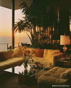 a living room filled with lots of furniture next to a large window overlooking the ocean