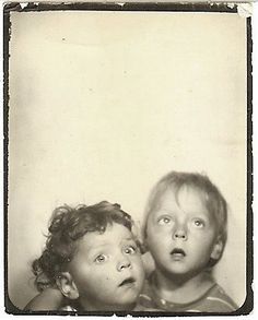 an old black and white photo of two young children looking at the camera with their mouths open