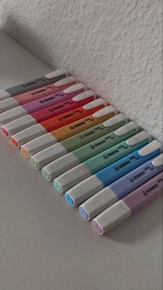 several different colored pens are lined up on the wall