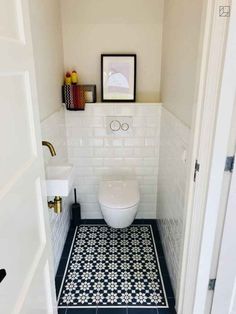 a white toilet sitting in a bathroom next to a black and white tile flooring