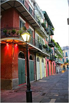 a lamp post in the middle of an alleyway with colorful buildings on both sides