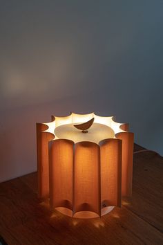 a lamp that is sitting on top of a wooden table next to a white wall