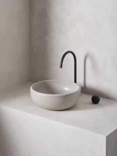 a white sink sitting on top of a counter next to a black faucet