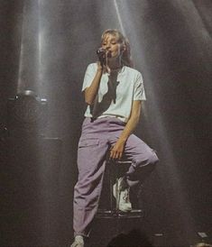 a man sitting on top of a stool in front of a microphone and spotlights