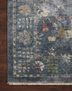 a blue rug with floral designs on the top and bottom, sitting on a wooden floor