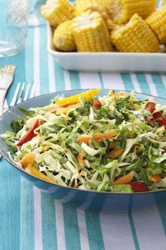 a salad with corn on the cob is served in a blue and white bowl