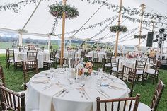 an outdoor tent set up for a wedding reception with white linens and floral centerpieces